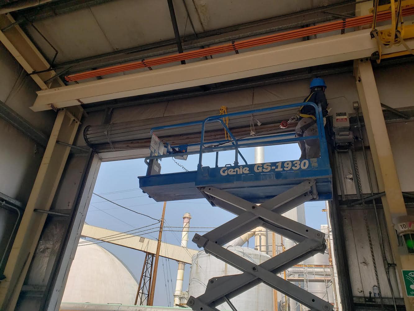 Technician on a scissor lift servicing a commercial overhead door