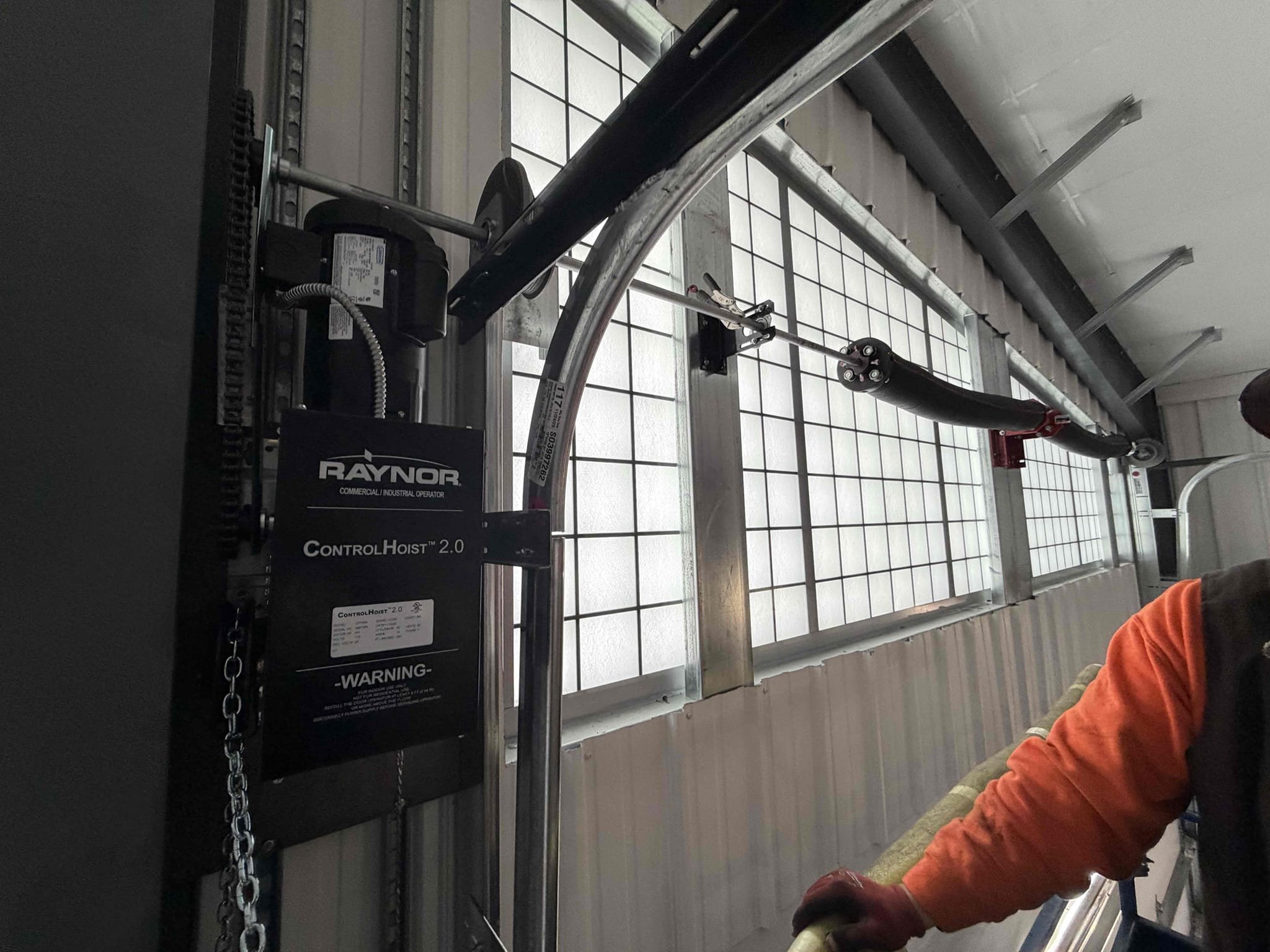 Raynor commercial door operator beside high-lift tracks and overhead door windows