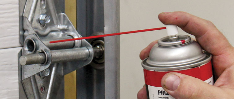 Lubricating a garage door hinge during fall maintenance
