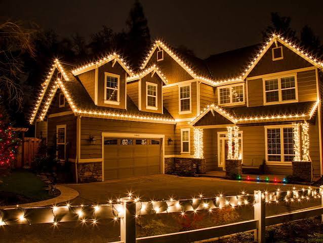 Home and garage outlined with holiday string lights at night